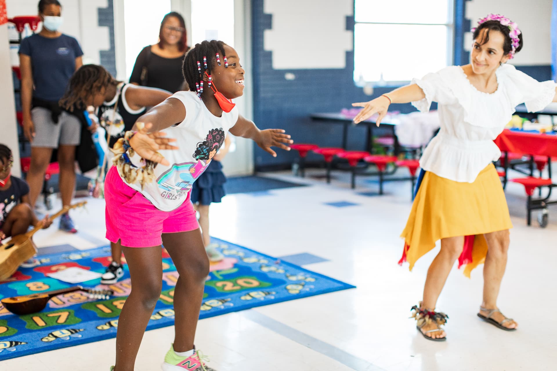 Angela guiding a young student through a joyful dance workshop