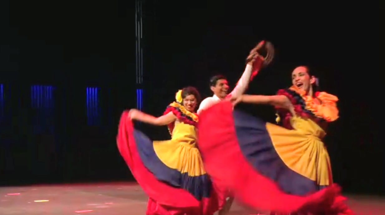 Performers twirling colorful skirts in a Colombian folk dance on stage