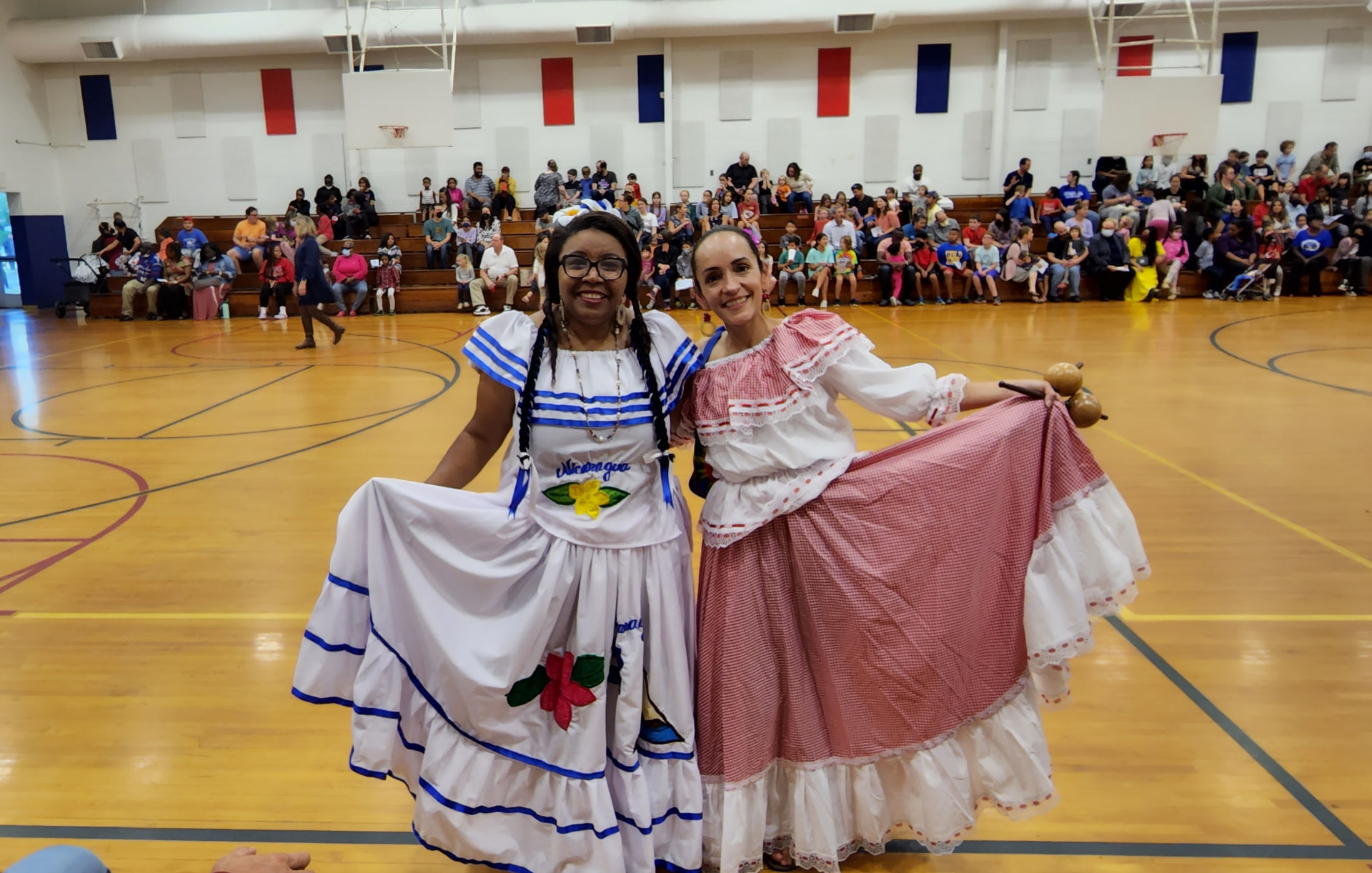 Angela and a fellow performer wearing folk dresses at a community celebration