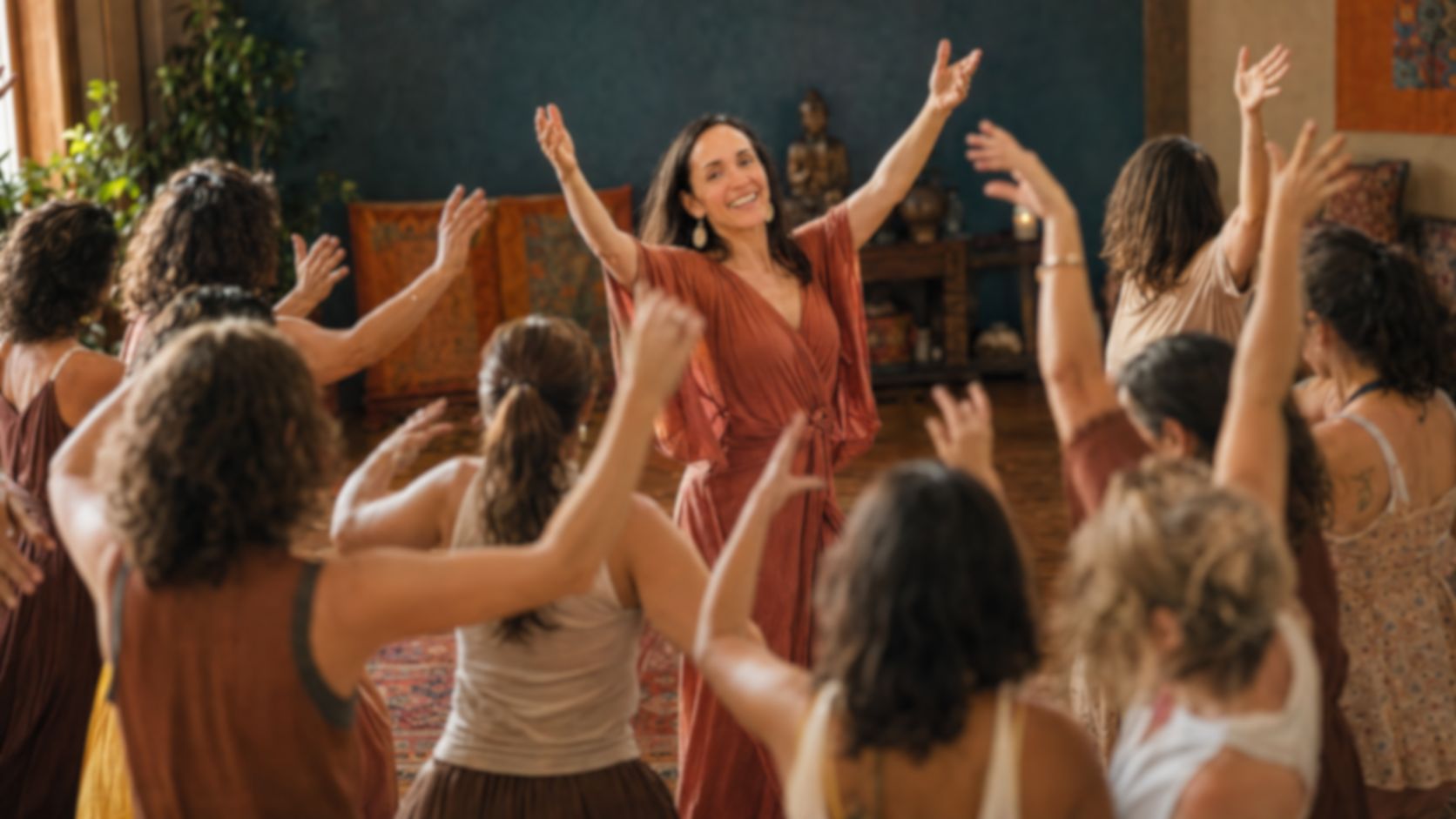 A circle of adults dancing together with raised hands in a warm community hall