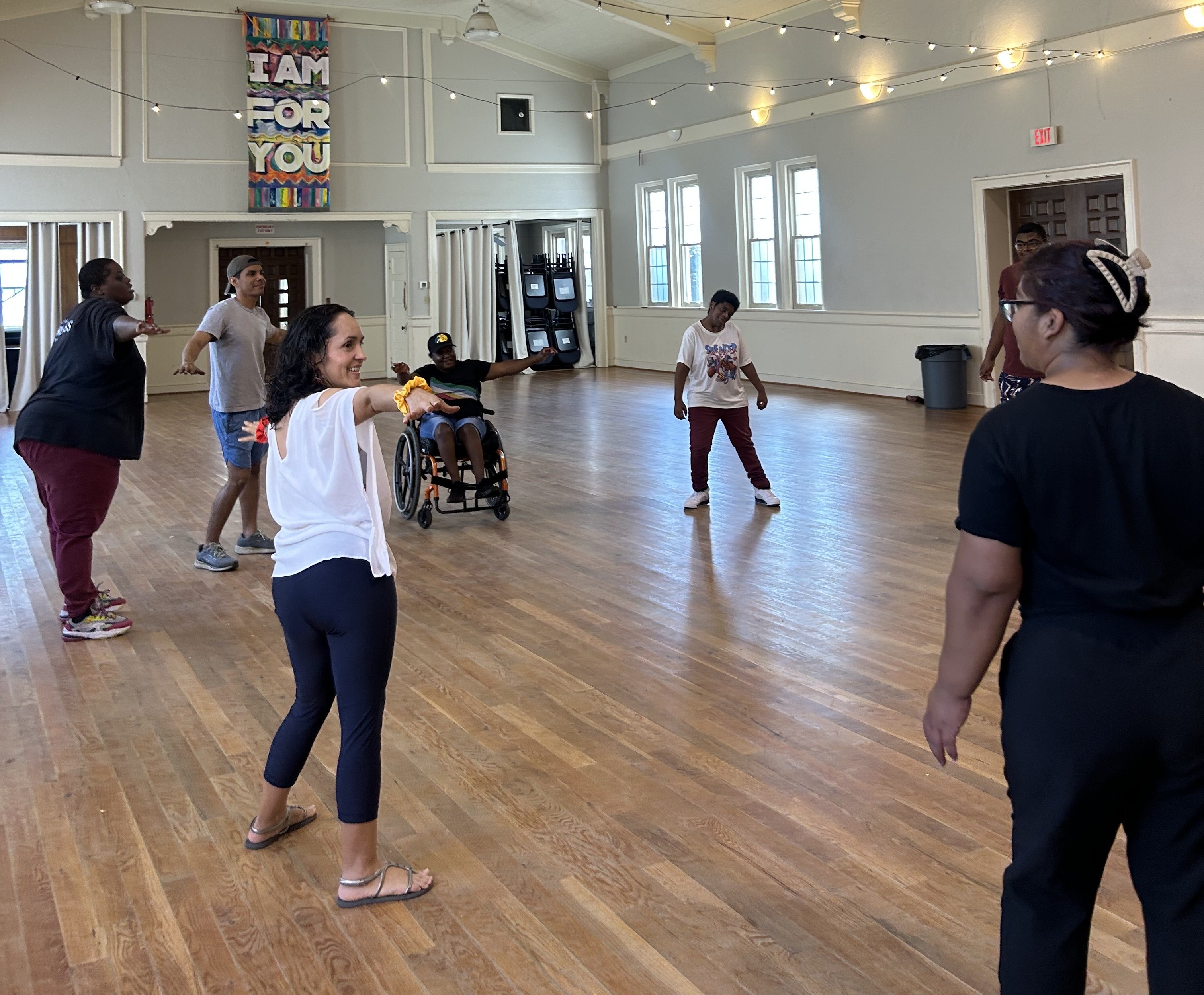 A group of adults moving together in a sunlit hall during a Dancefulness session